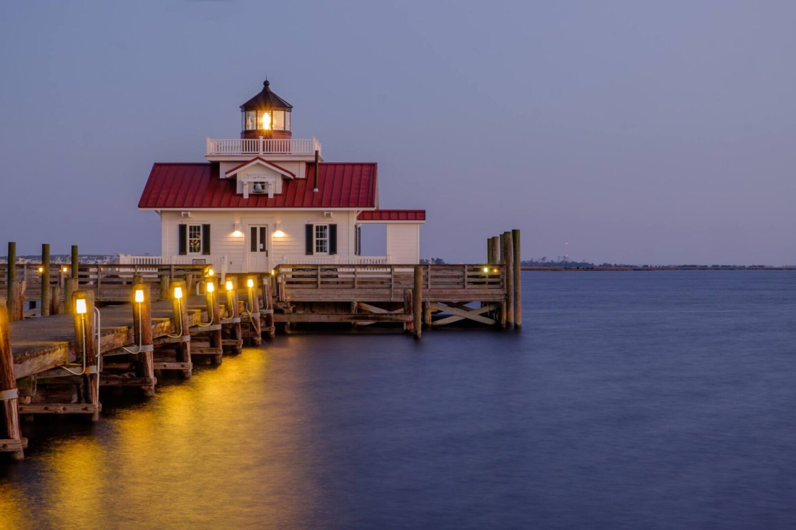 A lighthouse sitting on top of the water near a pier.