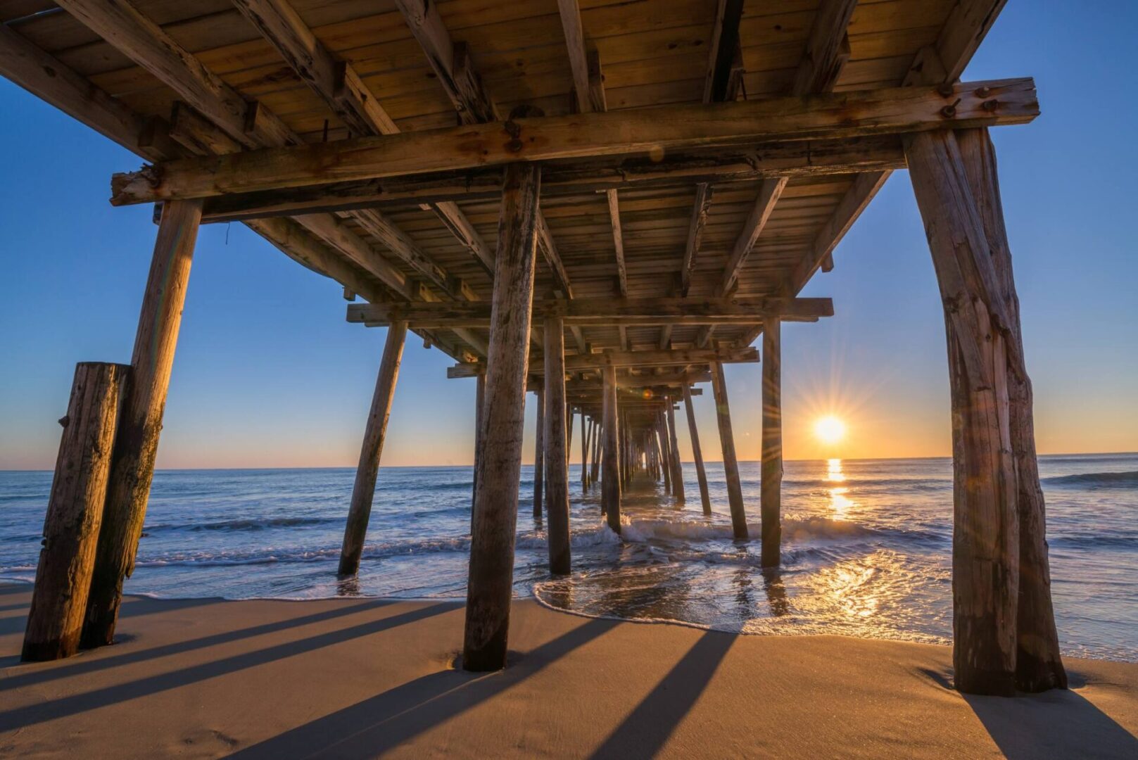 A pier with the sun setting over the ocean.