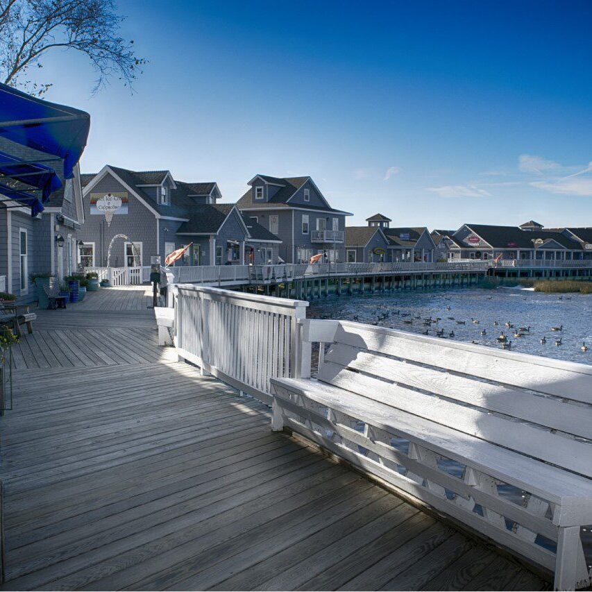 A wooden deck with benches and houses in the background.