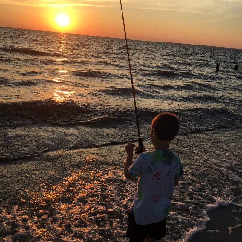Child fishing at sunset on beach