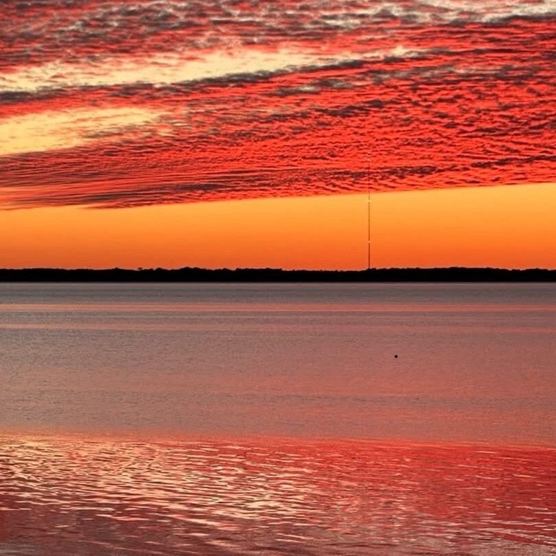 Vibrant red sunset over calm reflective water