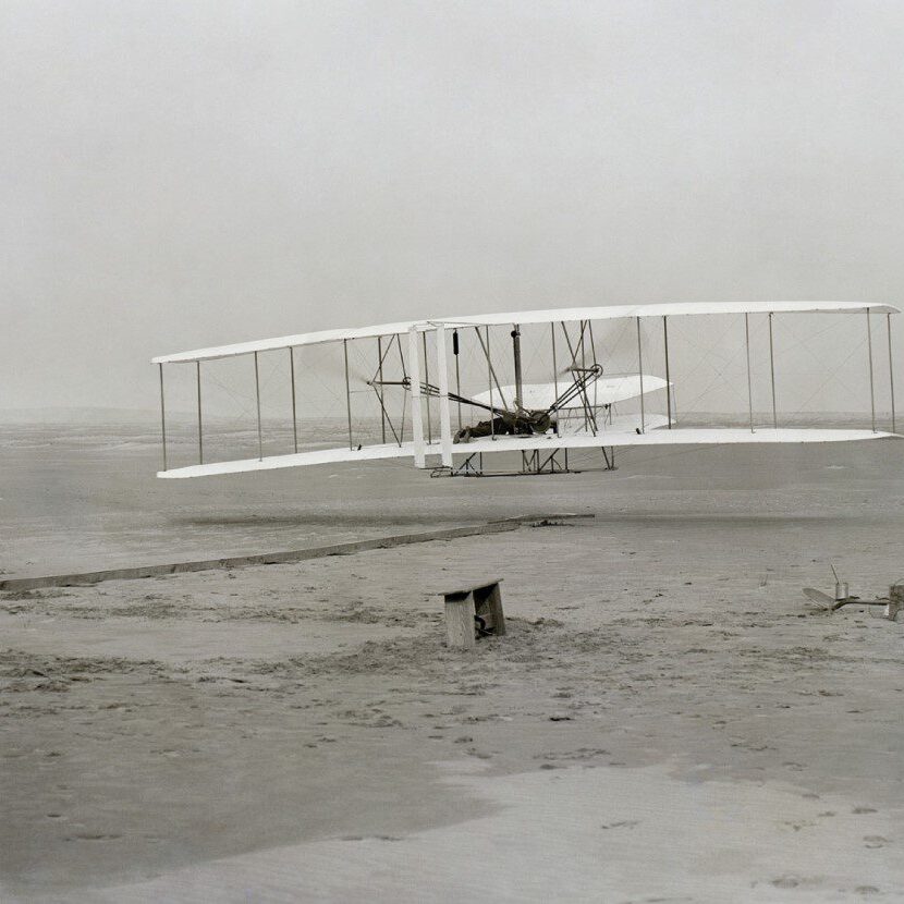 A white airplane flying over water in the fog.